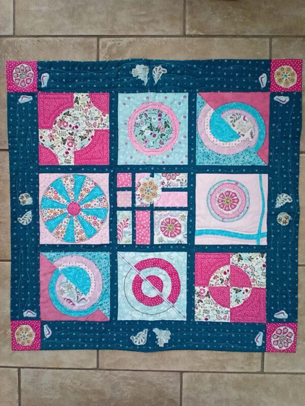 Sampler quilt using different circle techniques in each of 9 blocks. Blues, pinks and reds