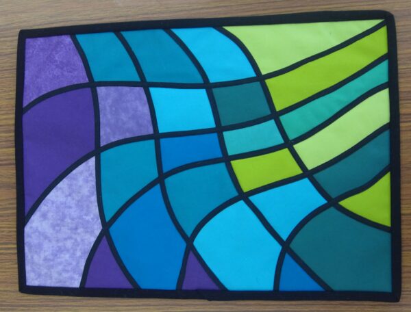 Stained glass applique quilt. Narrow black bias strips criss-crossing a purple, blue and green multi background.