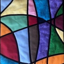 Stained glass applique quilt. Narrow black bias strips criss-crossing a multi background.